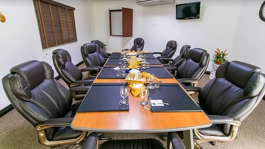 A conference room features a long, dark wood table surrounded by black office chairs | Board Room | Altamont Court, Jamaica