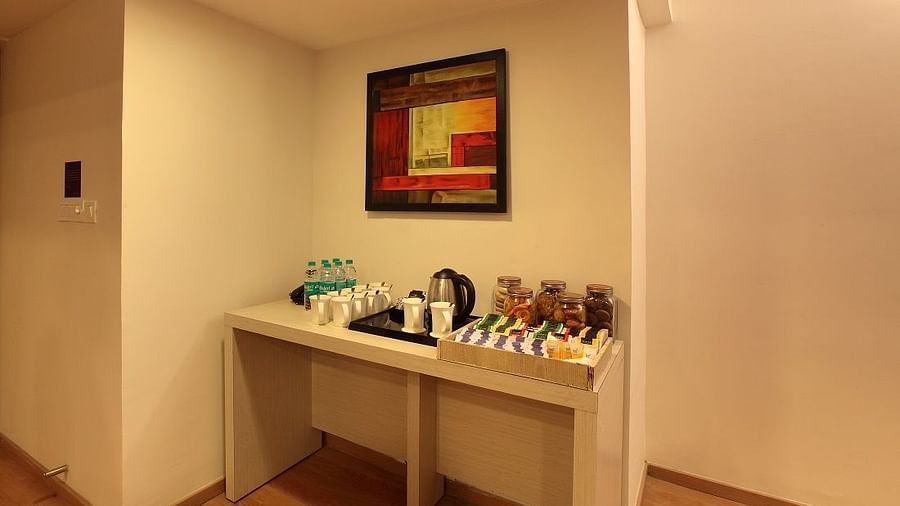 Table with a tea and coffee maker in a room at Starlit Suites, Bangalore