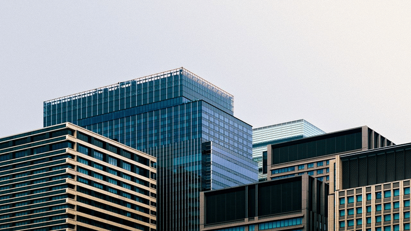 High-rise commercial buildings with layered glass and steel exteriors, representing an urban corporate hub with multiple office towers clustered together.