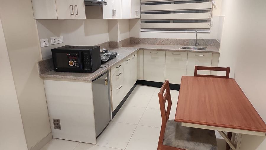 A kitchen consisting of a microwave, a chimney, a cooking stove, a sink and  a dining area - A M Suites