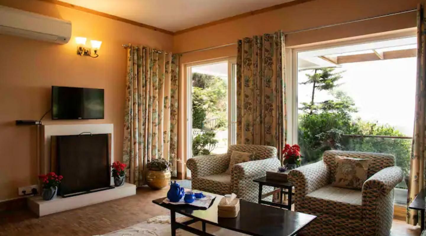 A living area with comfortable sofas near a cosy wooden fireplace at 3 BHK at SOUTHGATE KASAULI BY ZENQ.