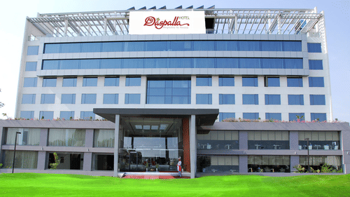Daspalla Hotel exterior with glass facade white building green lawn and welcoming entrance staff standing at the front door