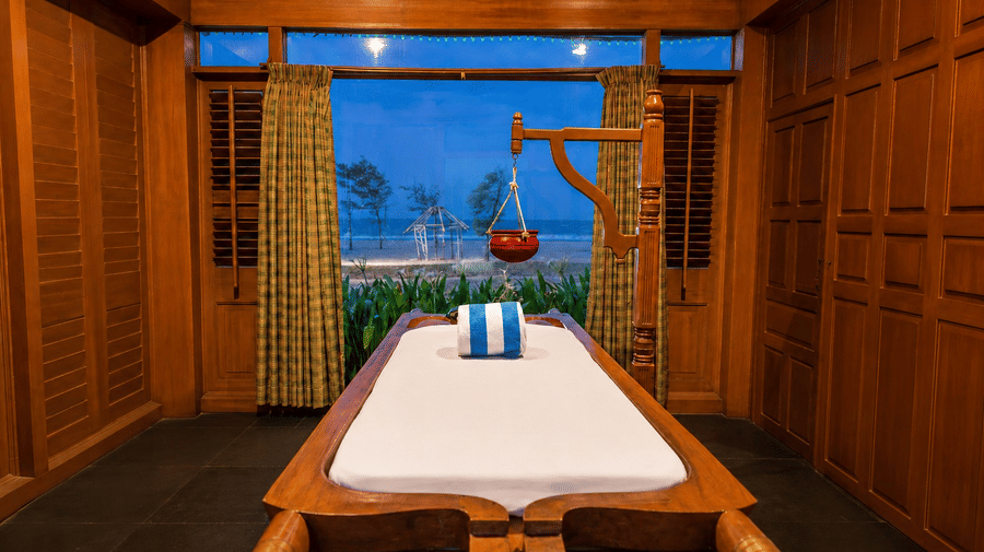 Spa massage room with warm wooden interiors and soft evening lighting at Chariot Beach Resort, offering a calm and relaxing ambiance.
