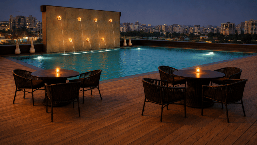 Rooftop dining near the swimming pool at The Empresa Hotel at dusk, with an illuminated fountain wall, candlelit tables and wicker chairs overlooking the city.