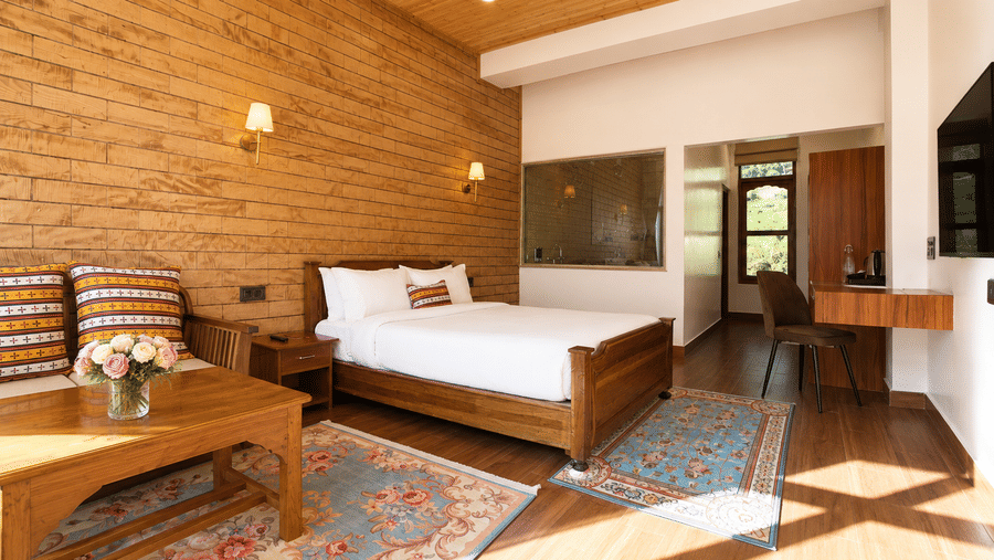 Junior suite at Summit Rungkhung Village Resort - The Signature Collection displaying a double bed, coffee table, armchairs, floor rug, side desk, and wall-mounted lights.