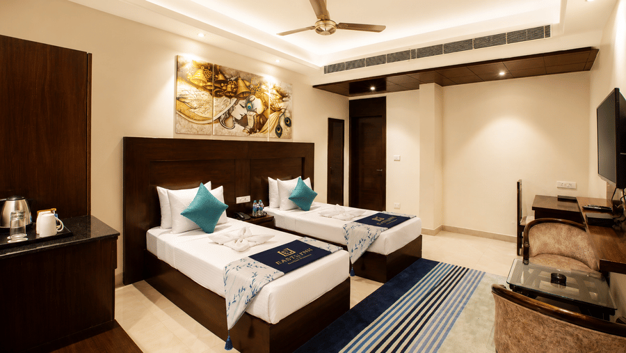 Deluxe Twin room with two single beds, artwork and a dressing table at Eastlynn Resort, Rishikesh.