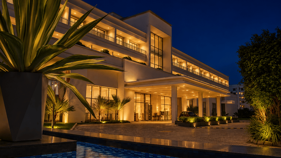 Exterior view of the illuminated main entrance and facade at night at Kiranshree Grand Hotel.