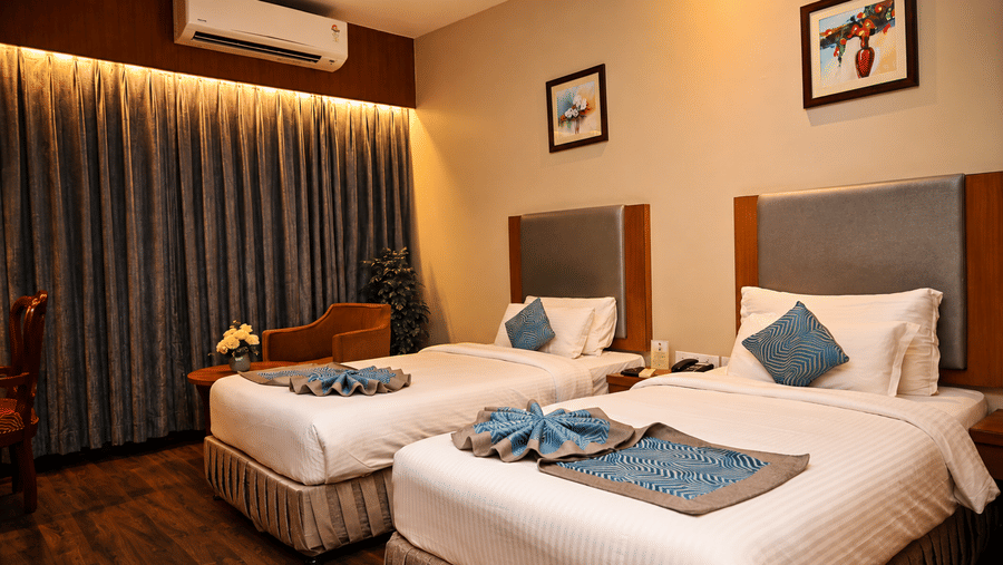 Club Superior Room with twin beds, blue accents, and modern amenities at Pipul Padmaja Premium Hotel, offering a comfortable stay.