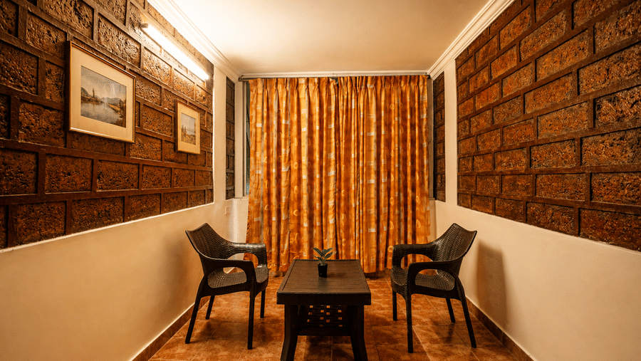 Cosy seating nook at Wind Chalet with two dark armchairs, small coffee table, exposed brickwork, and full curtains.