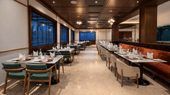 Wide angle view of Noor All-day Dining at Mountnoor Sarovar Premiere, Pahalgam, with neatly arranged tables and large glass windows offering views of the surroundings.