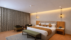 Bedroom of Superior Room with Bathtub furnished with a king size bed, a bench on a carpet, bedside tables, a seating area for 2, and 2 lights hung near the wall from the ceiling.