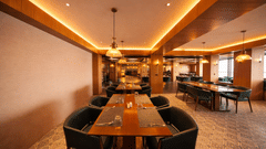 A dining room with rectangular tables, chairs, and illuminated ceiling panels | Pride Premier Darjeeling