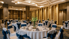 The banquet hall with round tables and chairs with blue sashes at Riviera Sarovar Portico, Pathankot.