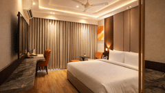 A Deluxe Room at Tulip Inn Gurugram featuring a large bed with linens, a dark marble desk, floor-to-ceiling curtains, and warm lighting.