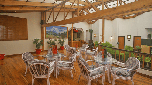 Well furnished Sunset Bar and Lounge at Central Heritage Resort and Spa, Darjeeling featuring several sets of table and chairs and a few flower pots at the corner