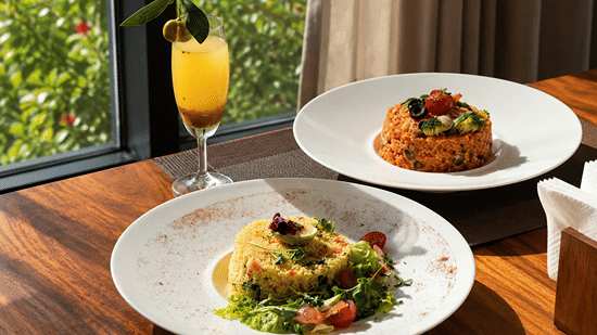 Farm to table plates of food on a wooden table placed alongside a vibrant beverage at Karma Lakelands.