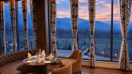 Views offered by Tamanna Kashmiri Speciality Lounge at Mountnoor Sarovar Premiere, Pahalgam, featuring a vibrant sky spread over the hilly landscape.