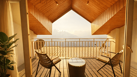 Room with balcony at Pride Premier Darjeeling featuring two chairs and a centre table facing towards the mountain view.
