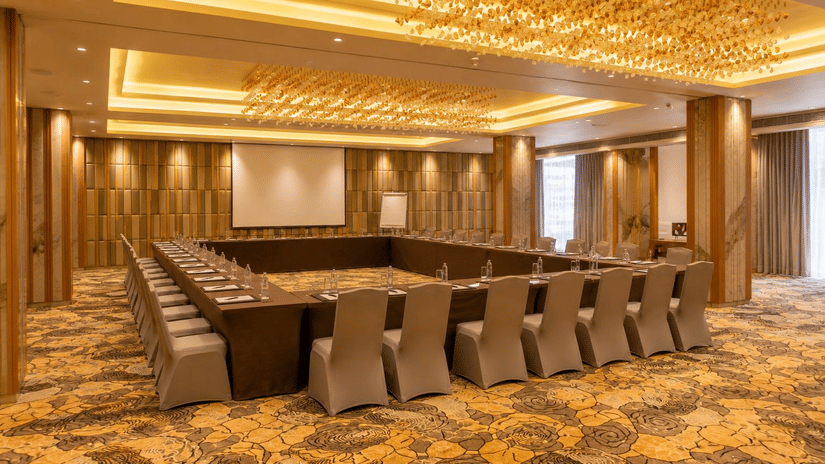 A spacious conference room is perfectly arranged with chairs and a screen - Pride Elite Himmatnagar, Gujarat
