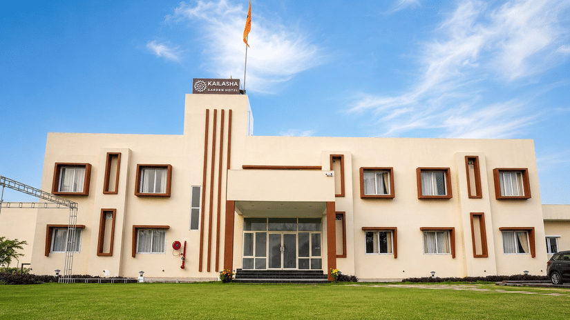 Hotel exterior with a spacious green lawn and clear blue sky.