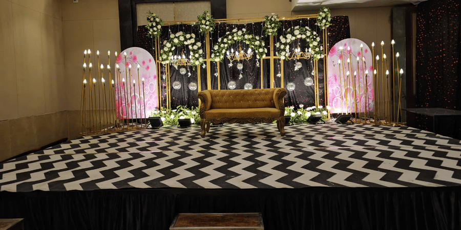Banquet hall pre-function area with a floral stage backdrop, decorative seating arrangements, and an event setup at Ambrosia Sarovar Portico, Haridwar.