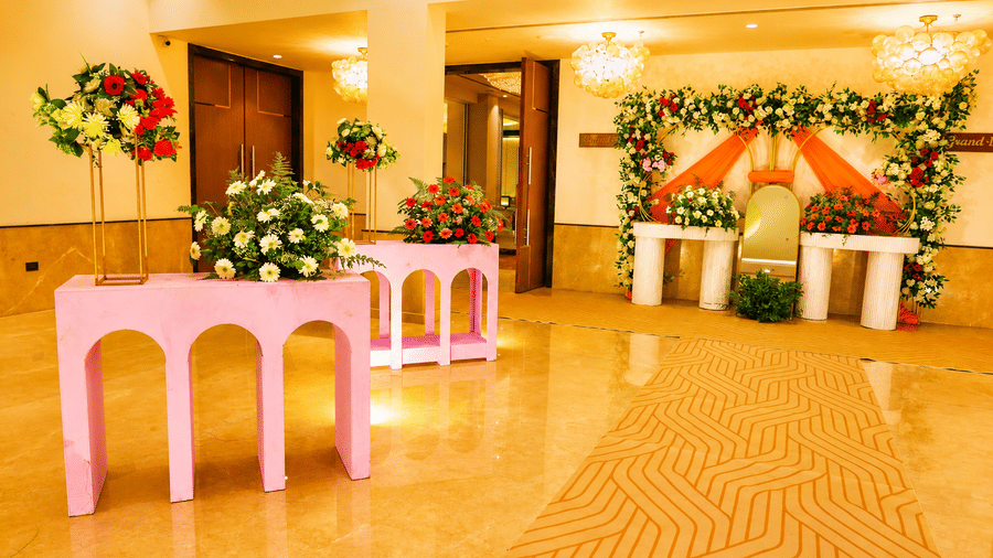 The banquet hall pre-function area with a floral stage backdrop and decorative event setup at Ambrosia Sarovar Portico, Haridwar.
