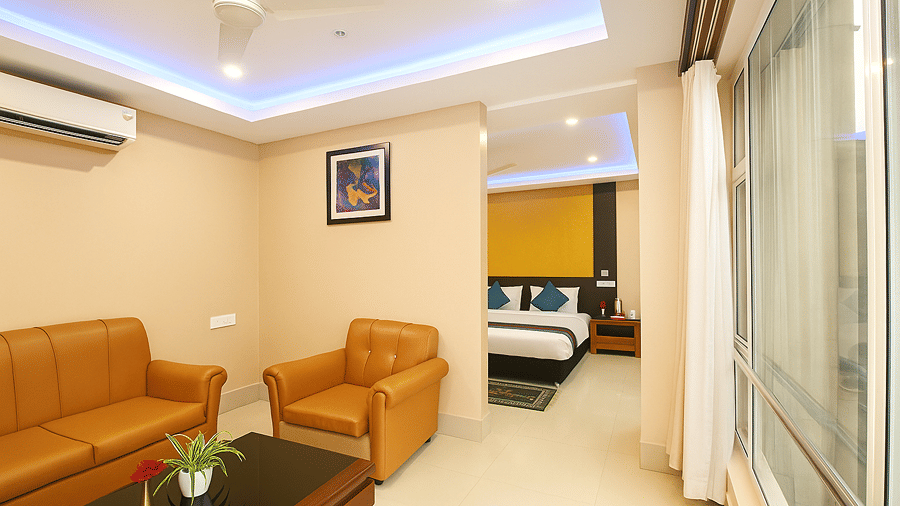 Suite with Sitting Room at Central Courtyard Boutique Hotel, Siliguri, featuring a sofa set around a coffee table in one room leading to the bedroom