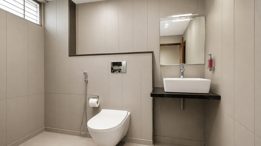 A modern bathroom at Central Hotels featuring grey tiled walls and flooring a wall-mounted toilet wash basin with mirror and grab rails in a clean and well-lit setting.