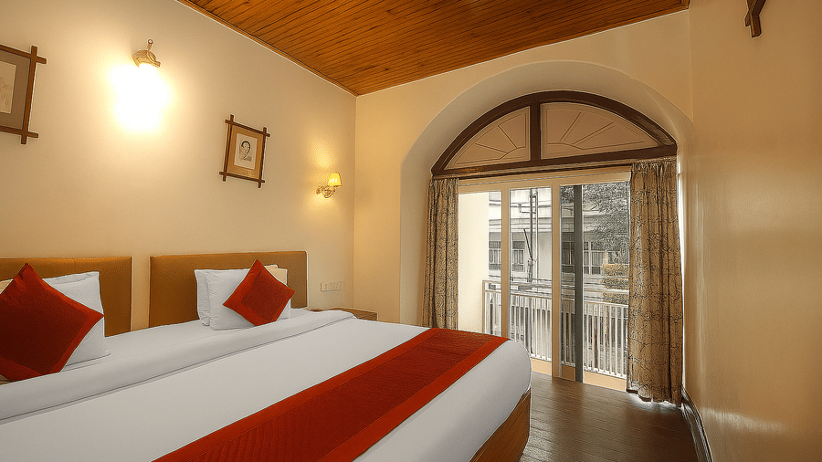 A room at Central Hotels featuring two beds with red and white bedding wooden ceiling an arched doorway leading to a balcony with warm wall lighting and dark hardwood flooring.