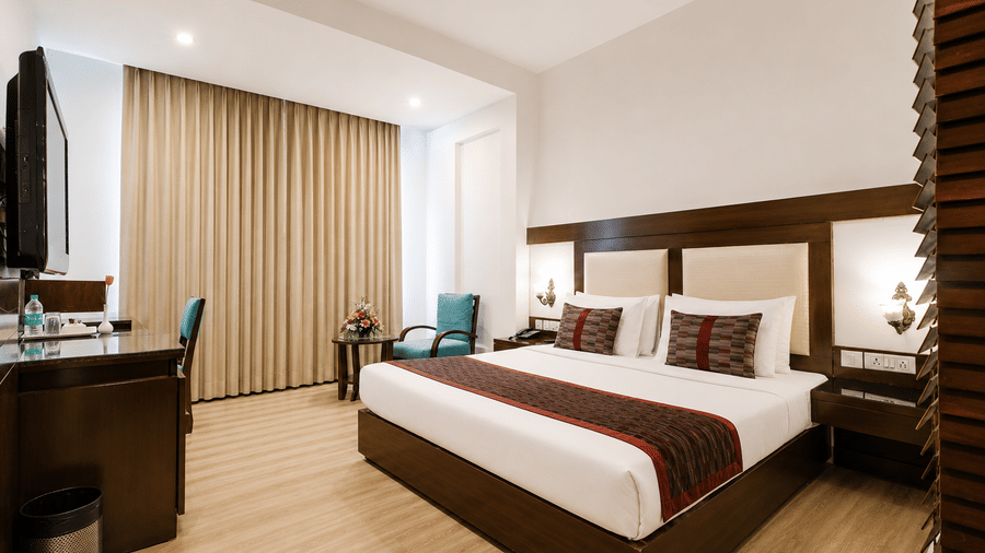 The Deluxe Room at HHI Varanasi with contemporary furnishings, twin beds, and bright spacious interiors.