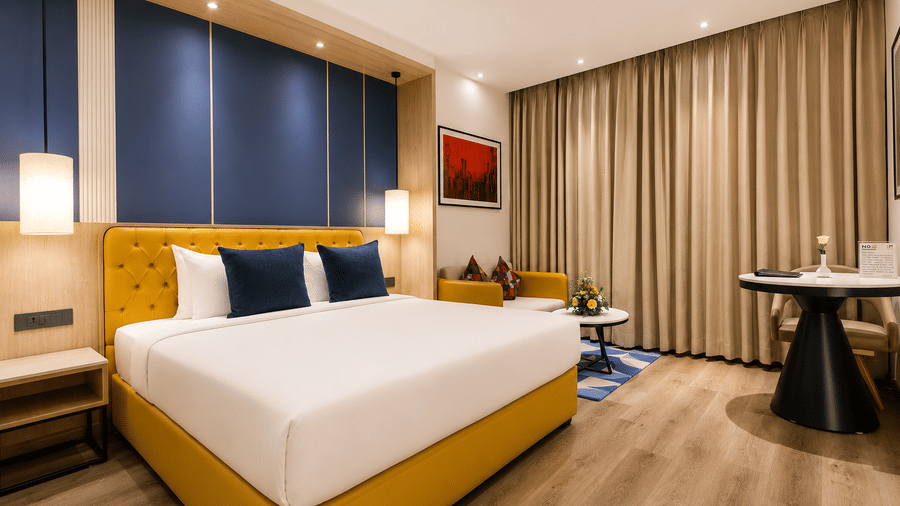 The Premium Room at Hotel Hindusthan International Varanasi showcasing modern interiors, a king bed, accent walls, and spacious comfort.
