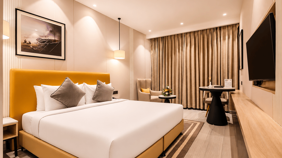 The Premier Room at Hotel Hindusthan International Varanasi with plush bedding, elegant decor, and a cosy seating corner.