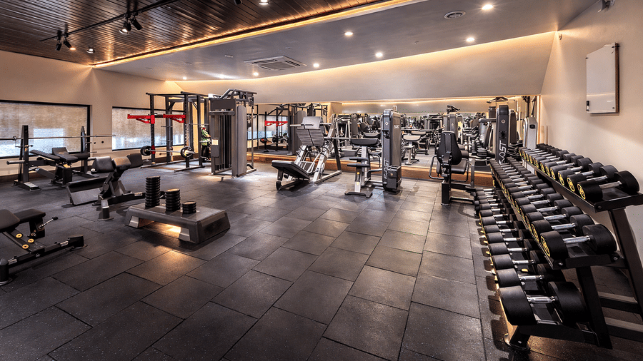 Indoor gym at Mountnoor Sarovar Premiere, Pahalgam, furnished with full-body gym equipments including racks of dumbbells, cycles, weight lifting, and treadmills.