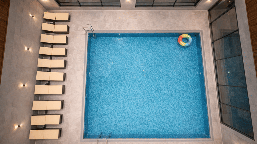 An overhead view of the indoor pool at Mountnoor Sarovar Premiere, Pahalgam, seen with a tube floatie on the water, and lounge chairs near the wall.