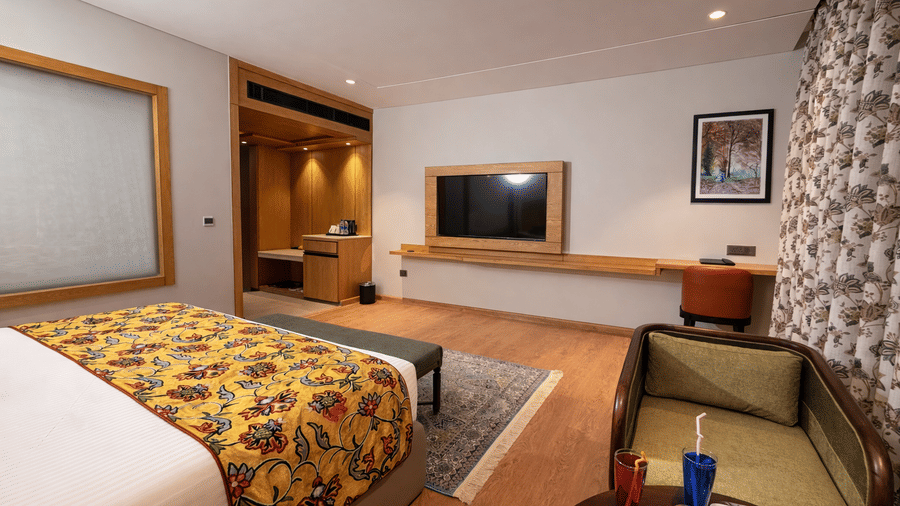 The plush king size bed in the Superior Room with Bathtub facing the wall-mounted television, work desk, and lit doorway | Mountnoor Sarovar Premiere, Pahalgam