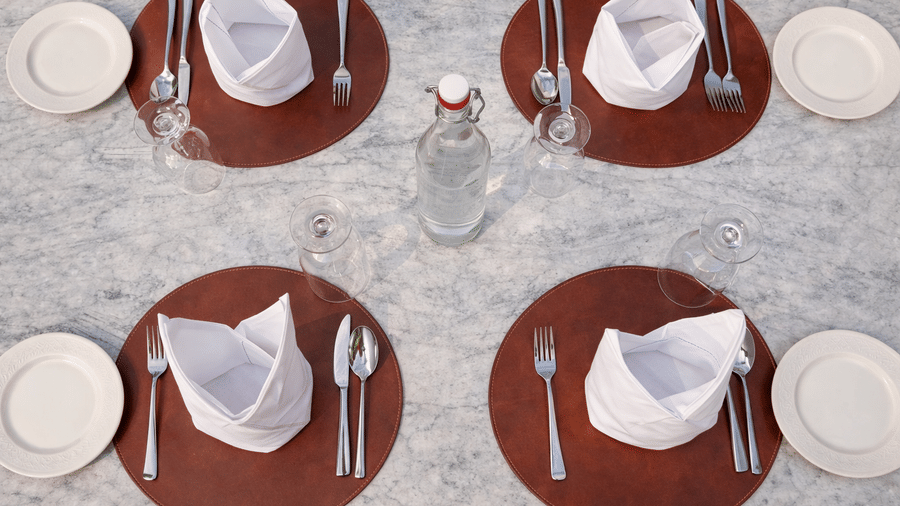 An overhead view of a table set with cutlery, small round plates, and folded kerchiefs at Noor All-day Dining in Mountnoor Sarovar Premiere, Pahalgam.