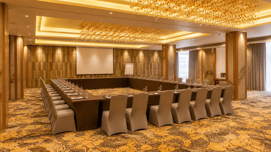 A spacious conference room is perfectly arranged with chairs and a screen - Pride Elite Himmatnagar, Gujarat