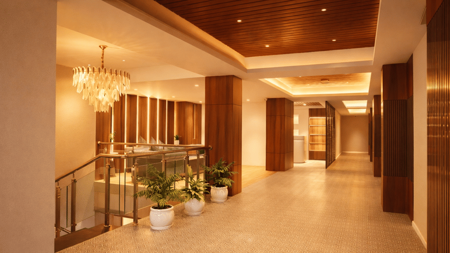 A hotel hallway showing a staircase with a glass railing and a decorative chandelier | Pride Premier Darjeeling