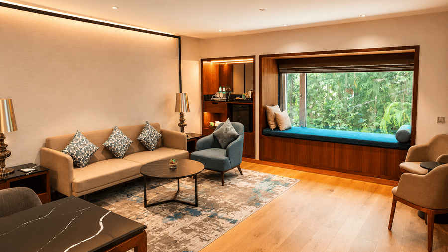 Spacious suite living area at Pride Premier Pune with sofas, armchairs, wooden flooring and a wide window.