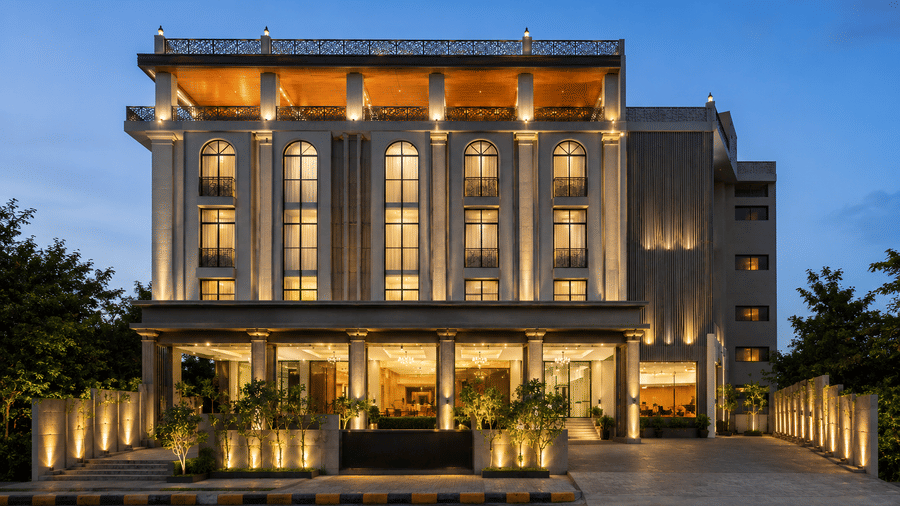 Exterior view of the multi-storey Tulip Inn Bidar building at dusk with illuminated facade lighting, entrance area, and surrounding trees.