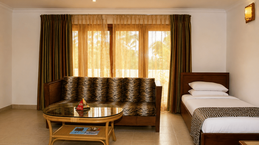 Family Room with a cozy sofa, wooden coffee table, and single bed at Chariot Beach Resorts, offering ample space for family relaxation.