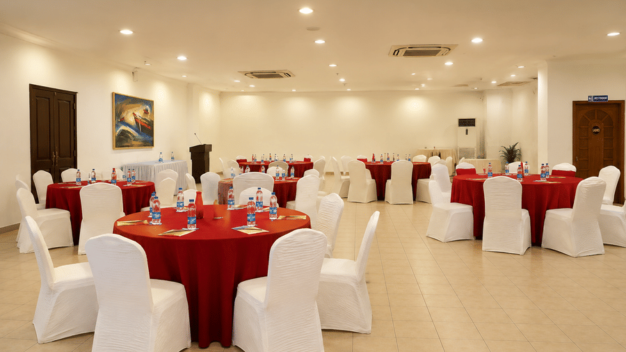 Pre Function Area set up with round tables in red linens and white chair covers at Chariot Beach Resort, perfect for hosting events.