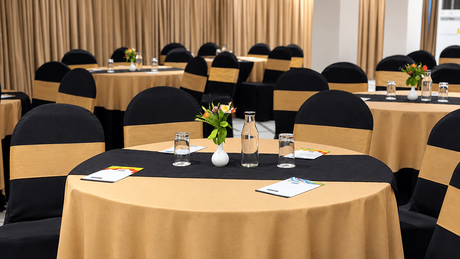 Close view of a round dining table with table settings and a floral centrepiece inside Sapphire Banquet Hall at Silver Sand Sentinel, Port Blair.