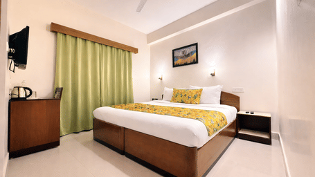 Standard Room at Summit Ttakshang Residency Hotel and Spa, Gangtok featuring a bed, a bedside table, a work desk and chair, and a flat TV screen.