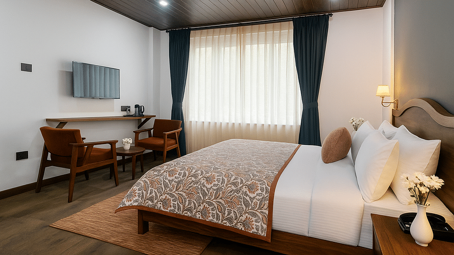 A spacious bedroom at Summit Enigma Resort & Spa features a large bed with a patterned throw, two armchairs and a coffee table, and large windows with dark green curtains.