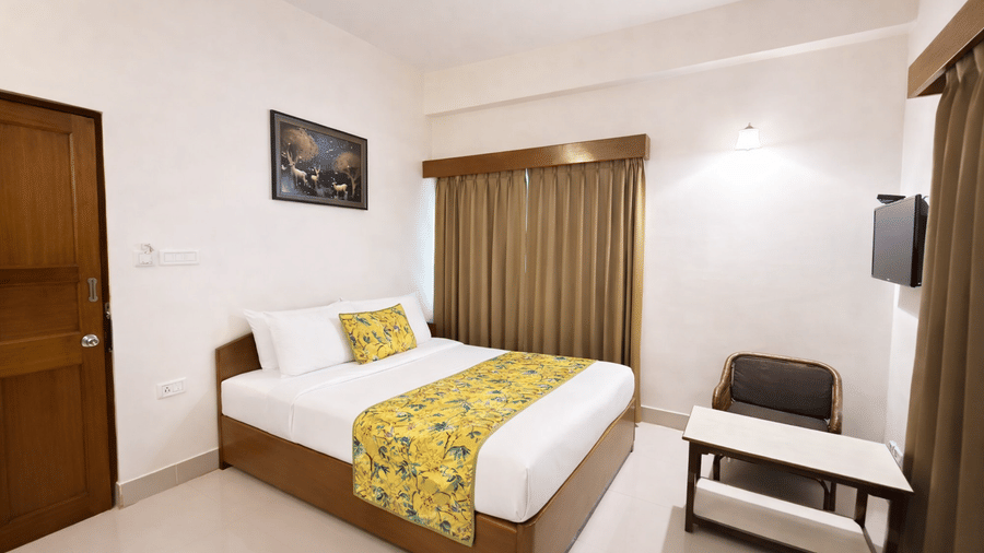 Standard Room at Summit Ttakshang Residency Hotel and Spa, Gangtok featuring a bed, and a seating area with sofa chair, table, and a flat TV screen.