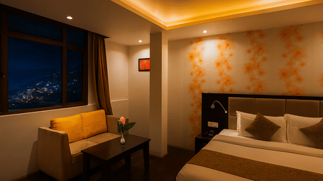 Stylish 3-star hotel room in Gangtok with cozy king-size bed, warm lighting, sofa seating, and large window offering night view of mountains and city lights