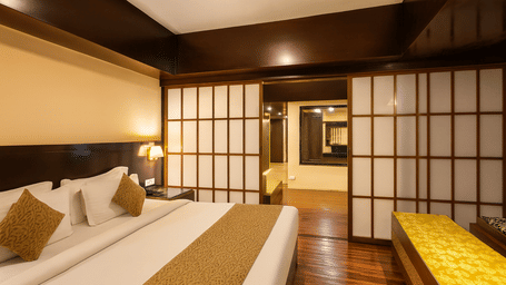 Premium hotel room with Japanese-inspired sliding wooden panels, king-sized bed, warm ambient lighting, and polished wooden flooring for a luxury 3-star stay in Darjeeling