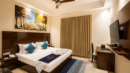 Executive Double room with a large bed, artwork and a work desk at Eastlynn Resort, Rishikesh.