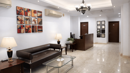 A lobby seating area with sofas, tables, and wall decor, at EMBLEM - Arjun Marg, Golf Course Road, Gurgaon.